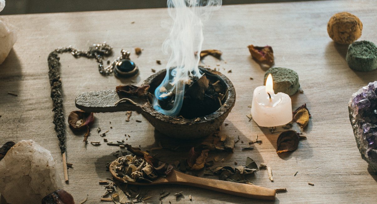 Résine d'encens fumante dans un brûle-parfum entouré de bougies et cristaux