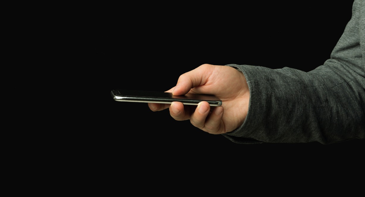 Main tenant un smartphone allumé dans l'obscurité le soir